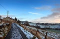 View of a snow covered narrow country lane with a row of stone houses surrounded by fields at hurst lane in hebden bridge Royalty Free Stock Photo