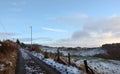 View of a snow covered narrow country lane with a row of stone houses surrounded by fields at hurst lane in hebden bridge Royalty Free Stock Photo