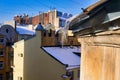 View of snow-covered roofs with spring icicles against blue sky