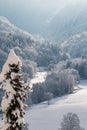 View into a snow-covered valley with light sunshine through the cloudy sky Royalty Free Stock Photo