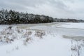 View of a snowy clearing  frozen lake and coniferous forest. Snow blizzard. Gloomy cloudy winter day Royalty Free Stock Photo