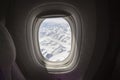 View of snowy mountains from a window of an airplane from inside Royalty Free Stock Photo