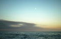 MOON AND CLOUDS OVER SEA AT SUNSET Royalty Free Stock Photo