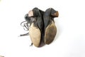 View of the soles of a vary old pair of women`s cloth and leather shoes, on white