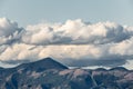 A view of some mountains top with some big, close clouds above t