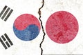 View of South Korea VS Japan national flags isolated on broken cracked concrete wall background