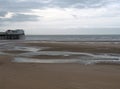 View of the south pier in blackpool with the beach at low tide in front of the sea and a cloudy sky