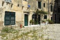 View of a square with grass growing everywhere in the old city in Corfu town in Greece, some white plastic chairs under a pergola Royalty Free Stock Photo