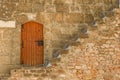 view of stairs in front of an old wooden door in a stone wall in the scenic city of Denia, Spain Royalty Free Stock Photo