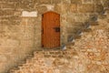 View of stairs in front of an old wooden door in a stone wall in the scenic city of Denia, Spain Royalty Free Stock Photo
