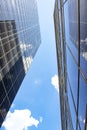 View standing between two tall glass skyscrapers looking straight up at both buildings reflecting each other and the sky - perspec Royalty Free Stock Photo