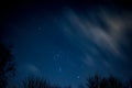 View of stars in a clear night sky with motion in clouds moving acroos the sky above Royalty Free Stock Photo