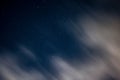 View of stars in a clear night sky with motion in clouds moving acroos the sky above Royalty Free Stock Photo