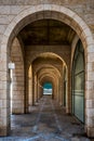 View of a stone-built covered corridor with gates and arches on a square in Tel Aviv Israel, with the contours of a surfer in the Royalty Free Stock Photo