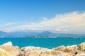 View from stone pier mole of Garda Lake azure water with Monte Baldo mountain range and Sirmione peninsula Royalty Free Stock Photo