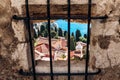 View through a stone window with iron bars of the old town rooftops Royalty Free Stock Photo