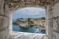 View from stone window of Lovrijenac fortress surrounded by blue sea and red rooftops and roofs of historic buildings of