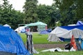 View of Strathcona Park in downtown Vancouver full of tents and homeless people with sign `Permanent solutions now` in the backgro