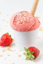 View of strawberry ice cream in white bowl with wafer on white table with strawberries and crumbles Royalty Free Stock Photo