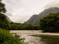 The view of the stream flows down through the forest on the mountain with cloud background at Kamikochi Japan Royalty Free Stock Photo