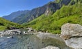 stream flowing in an alpine valley in green meadow and mountain range background Royalty Free Stock Photo