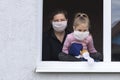 view from the street. In an open window, a woman holds a child, both masked. There is no way to take to the streets. Self-