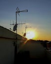 View of the sun setting from a terrace with several satellite dishes