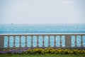 View from the Sunny promenade with flowers on the sea coast. Beautiful coast in the city. Stone pavement near the beach and the