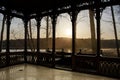 View of sunrise on the lake in spring from wooden openwork gallery or gazebo. Forest silhouettes and the rays of the rising sun