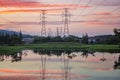 View before sunset with beautiful clouds and sun before the horizon. There are high voltage electricity poles and cables. Reflecti