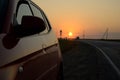 View of the sunset, country road and reflection of sunset on the side surface of a passenger car. The shot was taken in Russia. Royalty Free Stock Photo