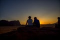 View of the sunset in the Jordanian desert Wadi-Rum, where a few people sit on a small mountain watching, and see how beautiful th