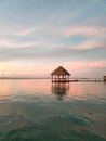 View of a sunset from lake Bacalar with a red and blue skyline and woody bridge, a roof in the water Royalty Free Stock Photo