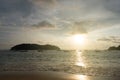 View of a sunset sky and silhouette of floating boats and small island on the beach as foreground