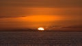 View of sunset with sun going down on the horizon with dramatic orange colored sky viewed from the coast of Taurito, Gran Canaria. Royalty Free Stock Photo