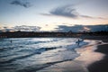 View of a surfing beach at dusk with illuminated skyline in the horizon
