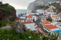 View of Sao Sebastiao church with Cape Girao with flowers on the foreground, in Camara de Lobos, Madeira