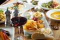 table of several entrees, potato chips, red wine, soup, salad