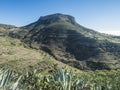 View on table mountain Fortaleza with surraunding villages Chipude and Pavon and Agave succulent plant leaves. Blue sky background Royalty Free Stock Photo