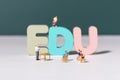 View of teacher and student figurines standing around EDU letters