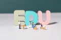 View of teacher and student figurines standing around EDU letters