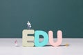 View of teacher and student figurines standing around EDU letters