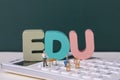 View of teacher and student figurines standing on a calculator around EDU letters