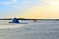 View of tents camping on ice of the river during ice fishing. Fishermen on frozen lake catch fish in hole of ice on the sunset Royalty Free Stock Photo