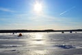 View of tents camping on ice of the river during ice fishing. Fishermen on frozen lake catch fish in hole of ice on the sunset Royalty Free Stock Photo