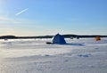 View of tents camping on ice of the river during ice fishing. Fishermen on frozen lake catch fish in hole of ice on the sunset Royalty Free Stock Photo