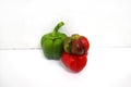 View of three shiny and fresh bell peppers next to each other, one green and one red, and the third a combination of green and red