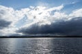 View of thunderstorm clouds above the lake. Cloudy sunset with sunbeams and blue sky. Royalty Free Stock Photo