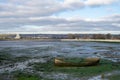 a view of tipner lake in Portsmouth, UK with an old wooden boat in the foreground at low tide also showing Brent Geese on the