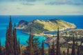 View to Assos village in sun light and beautiful blue sea. Cypress trees in foreground. Kefalonia island, Greece